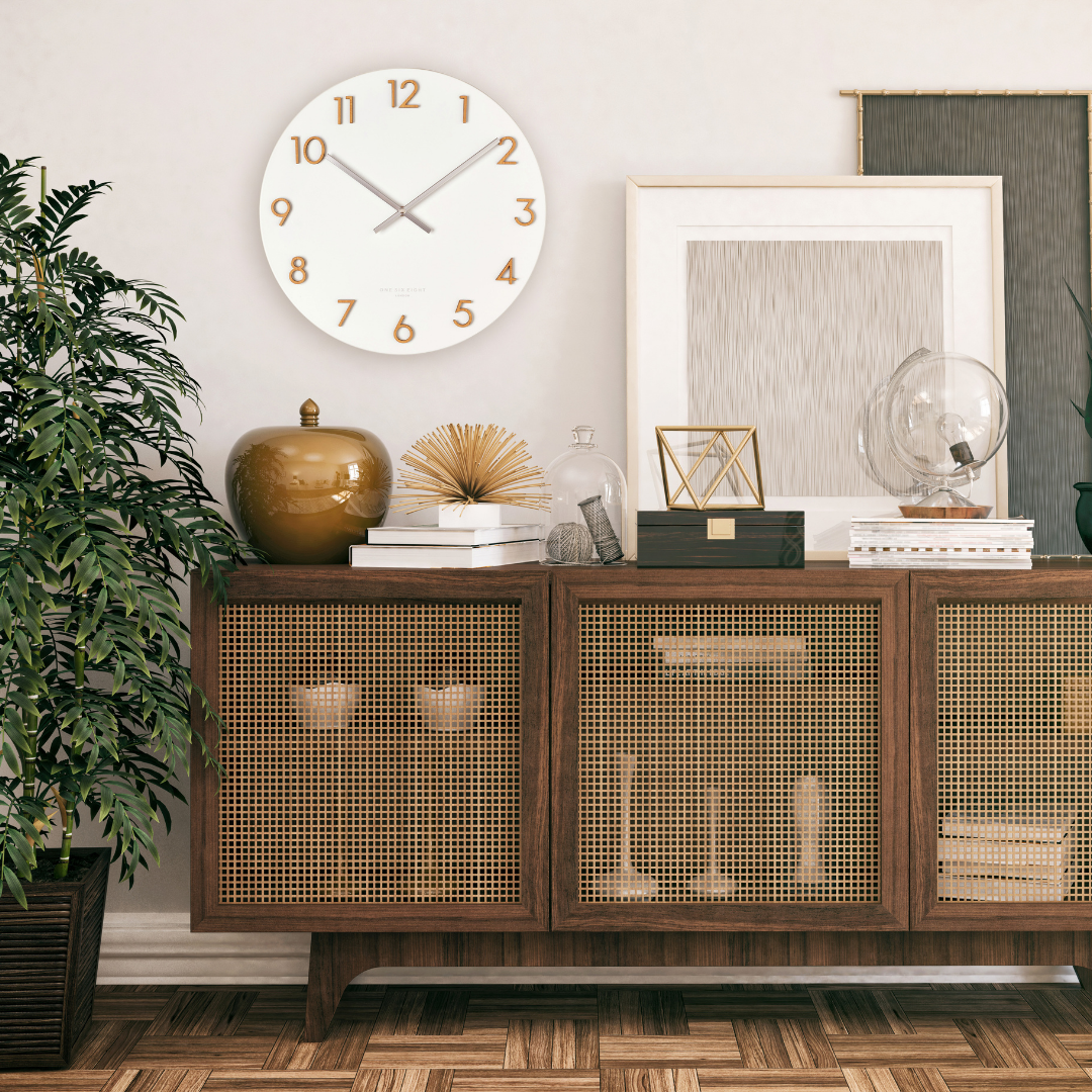 Katelyn wall clock in white with gold numerals, styled above a rattan-front sideboard